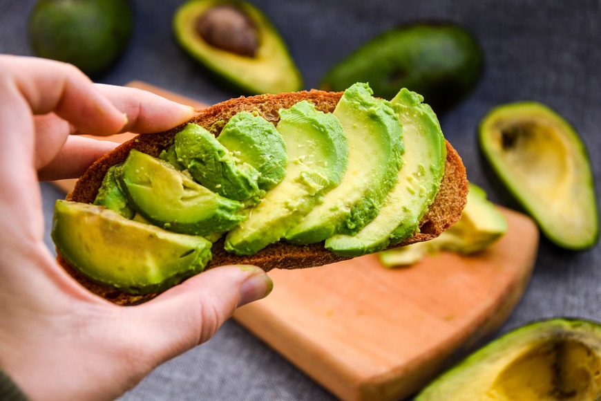 Female hand holding Avocado toast, green organic avocado Female hand holding Avocado toast, green organic avocado